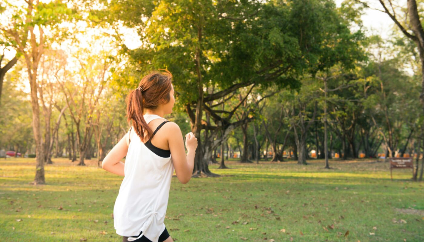 Femme en train de courir dans un parc au lever du soleil