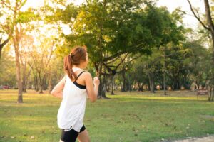 Femme en train de courir dans un parc au lever du soleil