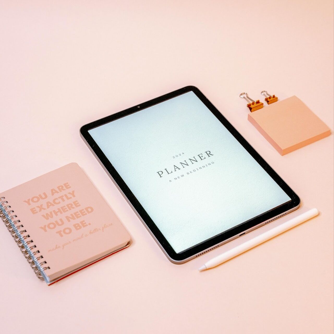 Tablette affichant un planner posée sur un bureau avec un carnet, un stylet et des notes adhésives