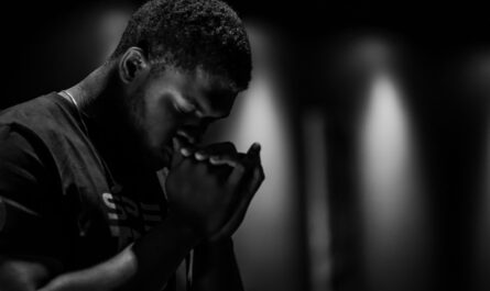 Homme les yeux fermés, les mains jointes devant son visage dans un environnement sombre