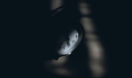 Réveil analogique partiellement visible dans l’obscurité, cadran éclairé en gros plan