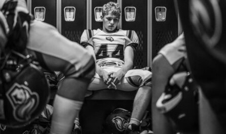 Joueur de football américain assis dans un vestiaire, entouré de ses coéquipiers