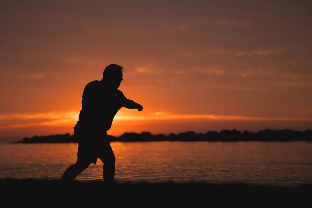 Silhouette d’un homme marchant au bord de l’eau au coucher du soleil