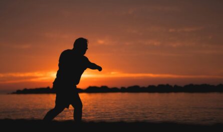 Silhouette d’un homme marchant au bord de l’eau au coucher du soleil
