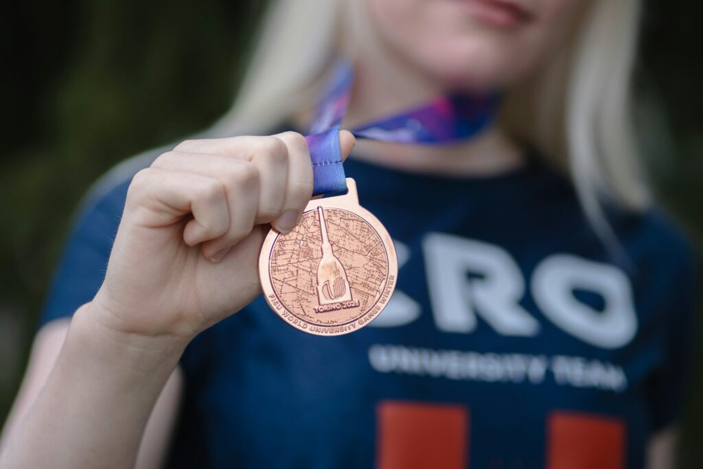 Personne tenant une médaille en bronze attachée à un ruban autour du cou